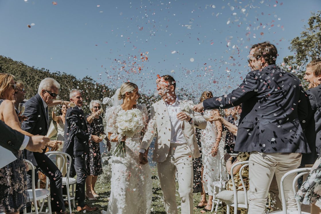 A ouple wlaking down the isle with people throwing confetti over the girl and guy