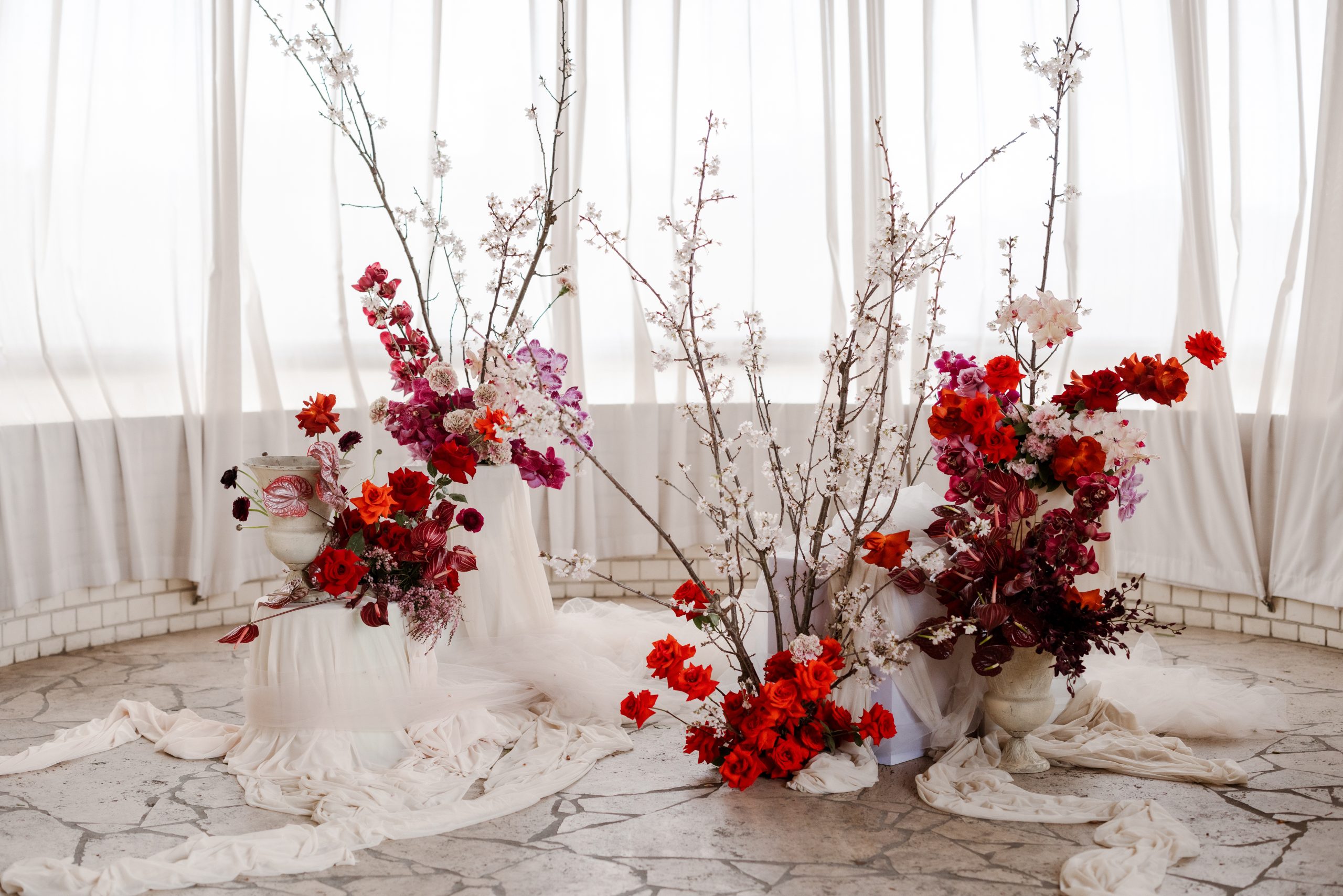 White curtains over the windows and on the floors with bright red and pink flowers and white cherry blossom trees.