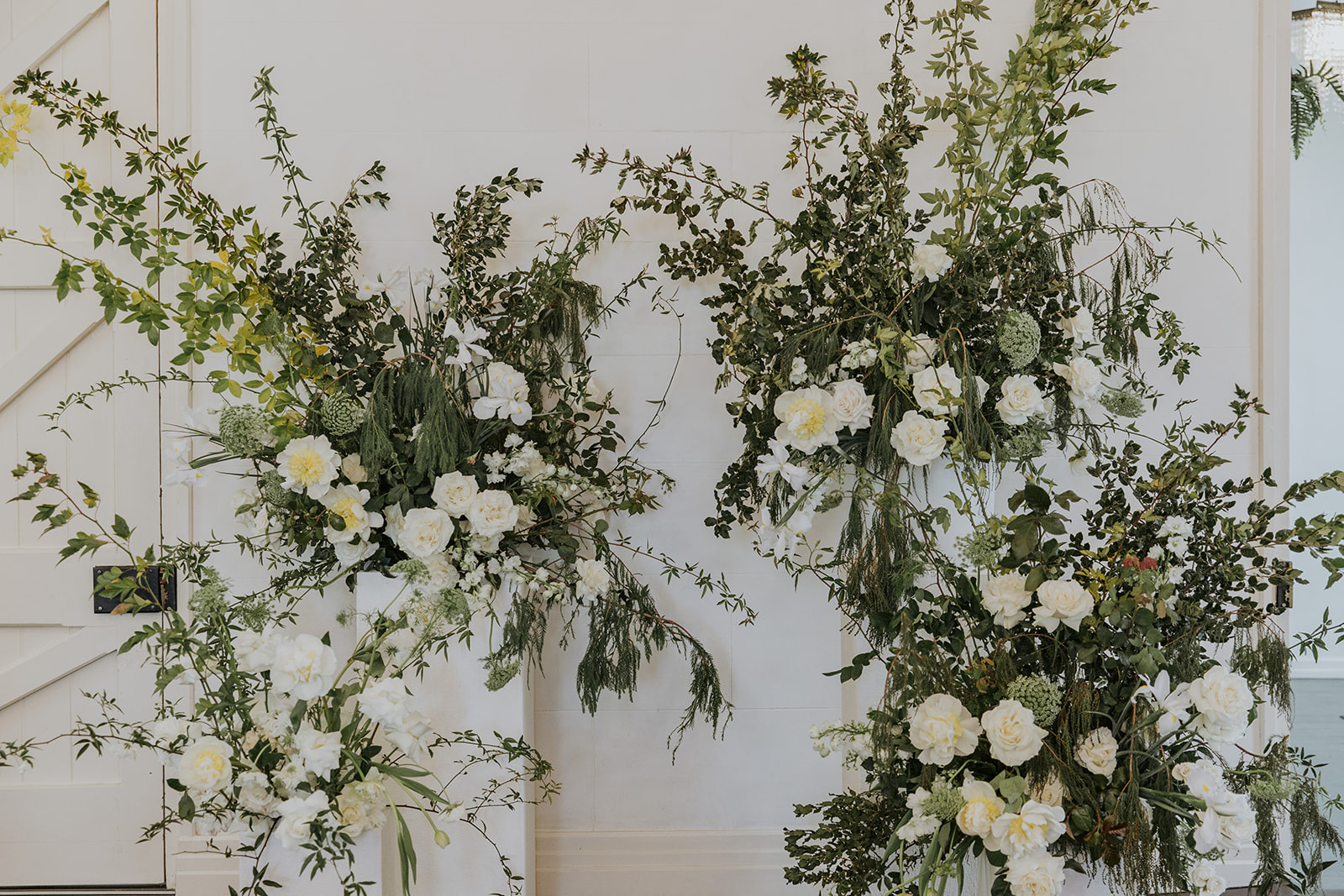 White wall in the background and green dried flowers everything and bright white flowers.